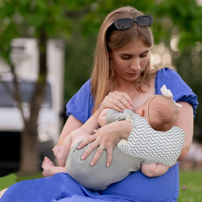 Bebe tetant coussin dallaitement Miemo sur le bras de maman au parc