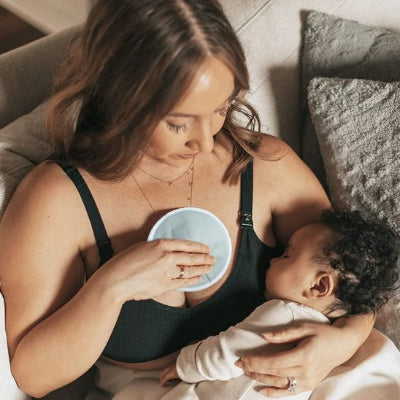 Maman tient un coussinet d'allaitement Couslum bebe dort dans ses bras