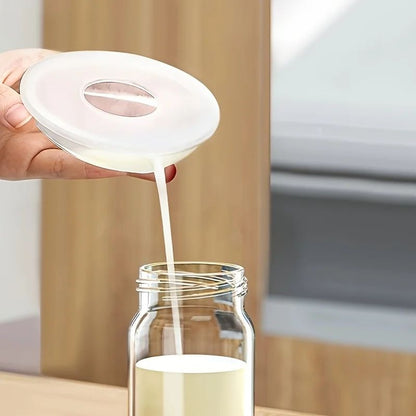 Maman verse le lait maternel recueilli de la coquille allaitement Shipresco dans un biberon 
